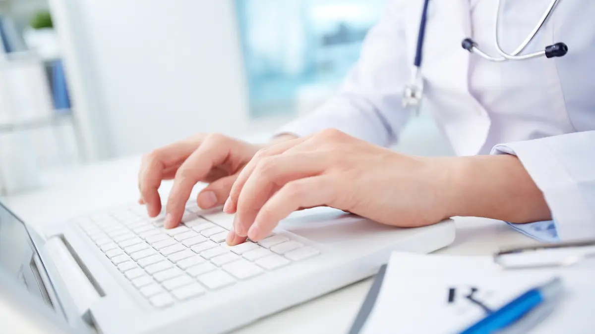 Close-up of a doctor in a white coat typing on a laptop keyboard, representing the use of technology in healthcare.